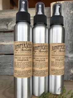 three silver spray bottles sitting on top of a wooden table