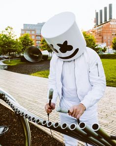 a man in a white suit is standing next to a bike with a bucket on his head