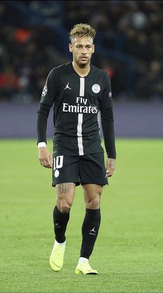 a man standing on top of a soccer field wearing black and white uniforms with yellow socks