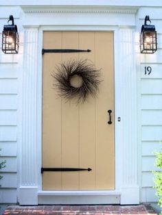 a front door with a wreath on it and two lights above the door that are lit up