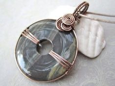 a wire wrapped pendant with an agate glass cabochle and spiral design on it