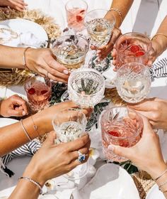 many people are holding wine glasses together