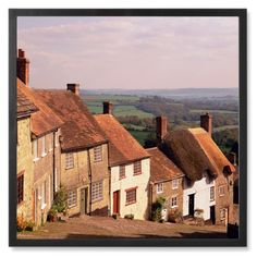 a row of houses with thatched roof tops in the country side, overlooking countryside