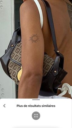 the back of a woman's shoulder with a small sun tattoo on her left arm