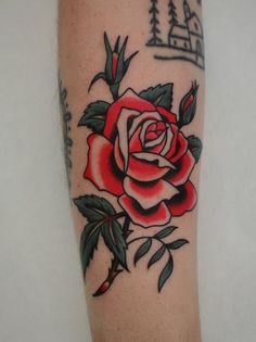 a red rose with green leaves on the arm is shown in this tattoo style photo