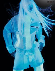 a woman with long white hair is standing in front of a black background wearing a blue outfit