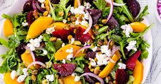 a salad with beets, carrots and feta cheese on top is shown