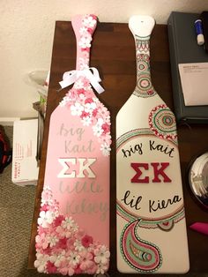 two decorated wine bottles sitting on top of a table next to each other with writing on them