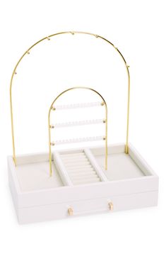 a white jewelry box with gold handles and an open drawer on the bottom that holds two pairs of earrings