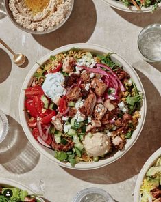 a table topped with bowls filled with different types of salads and dressings on top of it