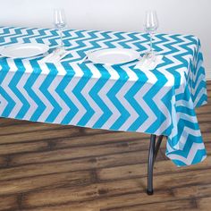 a blue and white chevron tablecloth with two empty plates on it in front of a wall