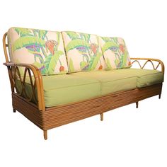 a wooden couch with green cushions on it's back and side panels that have tropical print