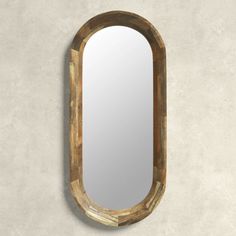 an oval mirror hanging on the wall next to a cement wall with a wooden frame