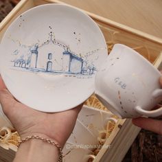 a person holding a white plate with a drawing on it and a cup in their hand