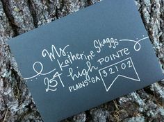 a chalkboard on the bark of a tree with words written in white and black ink