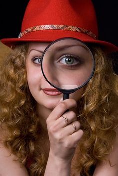 a woman wearing a red hat and holding a magnifying glass to her face