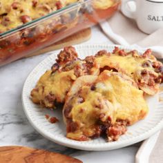 some food is on a white plate next to a glass casserole dish