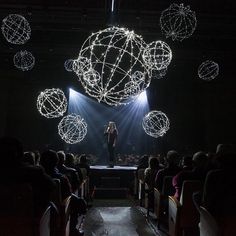 a woman standing on top of a stage in front of lots of balls and lights