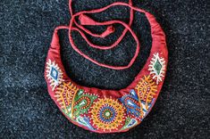 a red purse sitting on top of a black carpet covered in lots of colorful designs