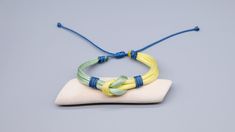 two bracelets are sitting on top of a piece of white wood and blue string