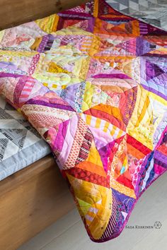 a bed with a colorful quilt on top of it