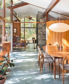 a dining room table and chairs in front of a stone wall with wood paneling