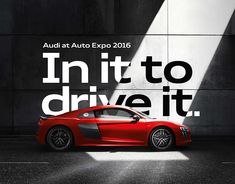 a red sports car parked in front of a wall with the words audi at auto expo 2016