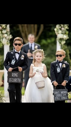 two young children dressed in formal wear standing next to each other at an outdoor ceremony