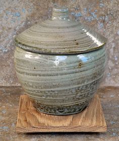 a large green vase sitting on top of a wooden stand