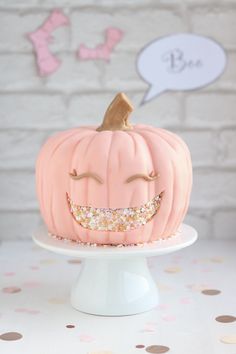 a pink pumpkin decorated with gold glitters and a smile on it's face