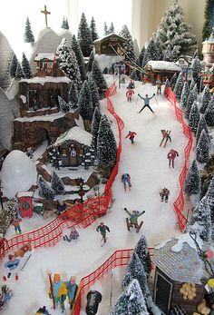 a toy ski resort with people skiing and snowboarding on the slopes in front of trees