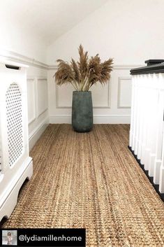 a plant in a vase sitting on the floor next to some white railings and stairs