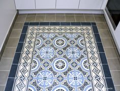 a tile floor with blue and white designs in the center, on top of a tiled floor