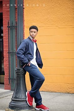 a young man leaning on a lamp post