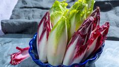 a blue bowl filled with lettuce on top of a gray cloth covered table