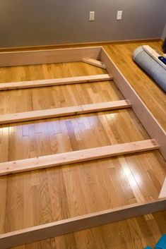 an unfinished bed frame on the floor in a room with hard wood floors and walls