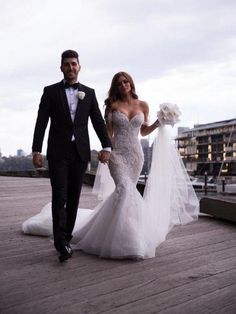 the bride and groom are walking down the pier