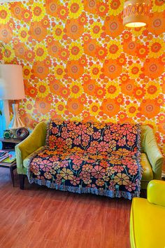 a living room with an orange and yellow floral wallpaper on the walls, couches and chairs