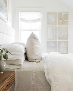 a bed with white linens and pillows in a small room next to a window