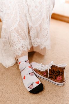 a woman's feet wearing white shoes with hearts on them