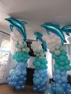 some blue and white balloons are in the air with dolphins on them as decorations for a party