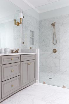 a bathroom with marble counter tops and gray cabinets