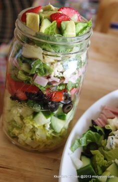 a salad in a mason jar next to a bowl of salad