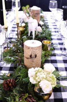 the table is set with candles and greenery