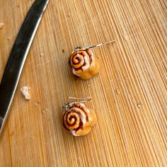 two cinnamon buns sitting on top of a cutting board next to a knife