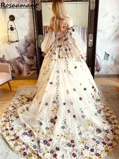 a woman is standing in front of a mirror wearing a dress with flowers on it