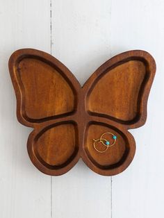 a wooden butterfly shaped tray with two rings on it