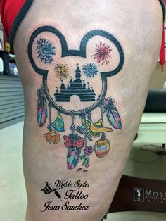 a mickey mouse tattoo on the back of a person's leg with fireworks and decorations