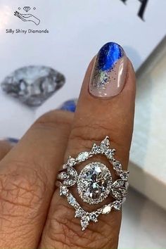 a woman's hand with blue and white nail polish holding a ring on her finger