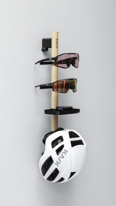 three pairs of sunglasses hanging on a wall with a helmet and other items attached to it